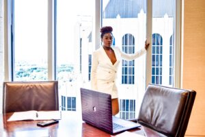woman in white blazer standing near window